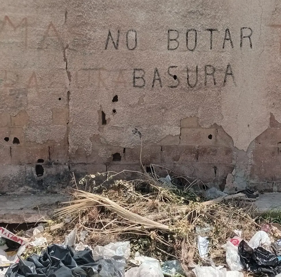 close up de aviso en la pared de bloques de "no botar basura2 en medio de basura como imagen del fotorreportaje avisos callejeros latinoamericanos creatividad ilimitada de la seccion encuadre del medio digital el pajarto azul