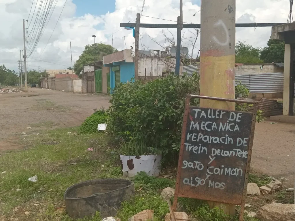 aviso de taller mecanico hecjo en lata y puesto sobre un psoste en medio de la calle como imagen de fotorreportaje de avisos callejeros latinoamericanos de seccion encuadre del medio digital el pajaro azul