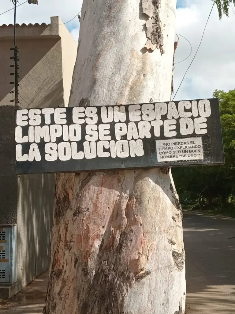 Cartel callejero latinoamericano atado a un árbol con el mensaje “Este es un espacio limpio, sé parte de la solución”, fotografiado para el reportaje gráfico Encuadre de El Pájaro Azu