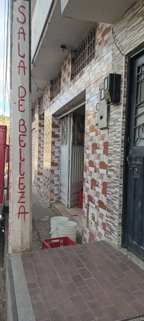 Mensaje pintado a mano en un poste de concreto en un barrio popular latinoamericano, reflejo de la creatividad urbana cotidiana en el reportaje Avisos Latinoamericanos, se lee sala de belleza