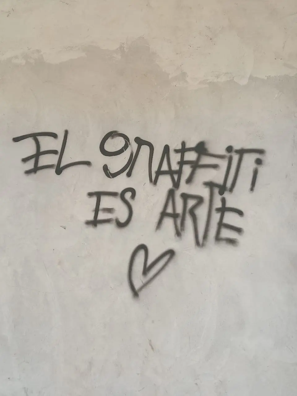 graffiti en tinta negra sobre pared blanca se ve dintel a un lado y se lee el graffiti es arte, seccion encuadre del fotorreportaje avisos callejeros latinoamericanos. creatividad ilimitada de el pajaro azul medio digital de cronicas y reportajes
